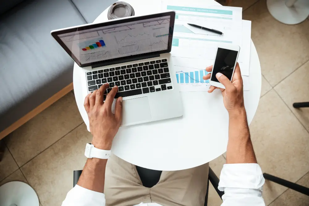 Visão de cima de pessoa lendo blog em celular e notebook